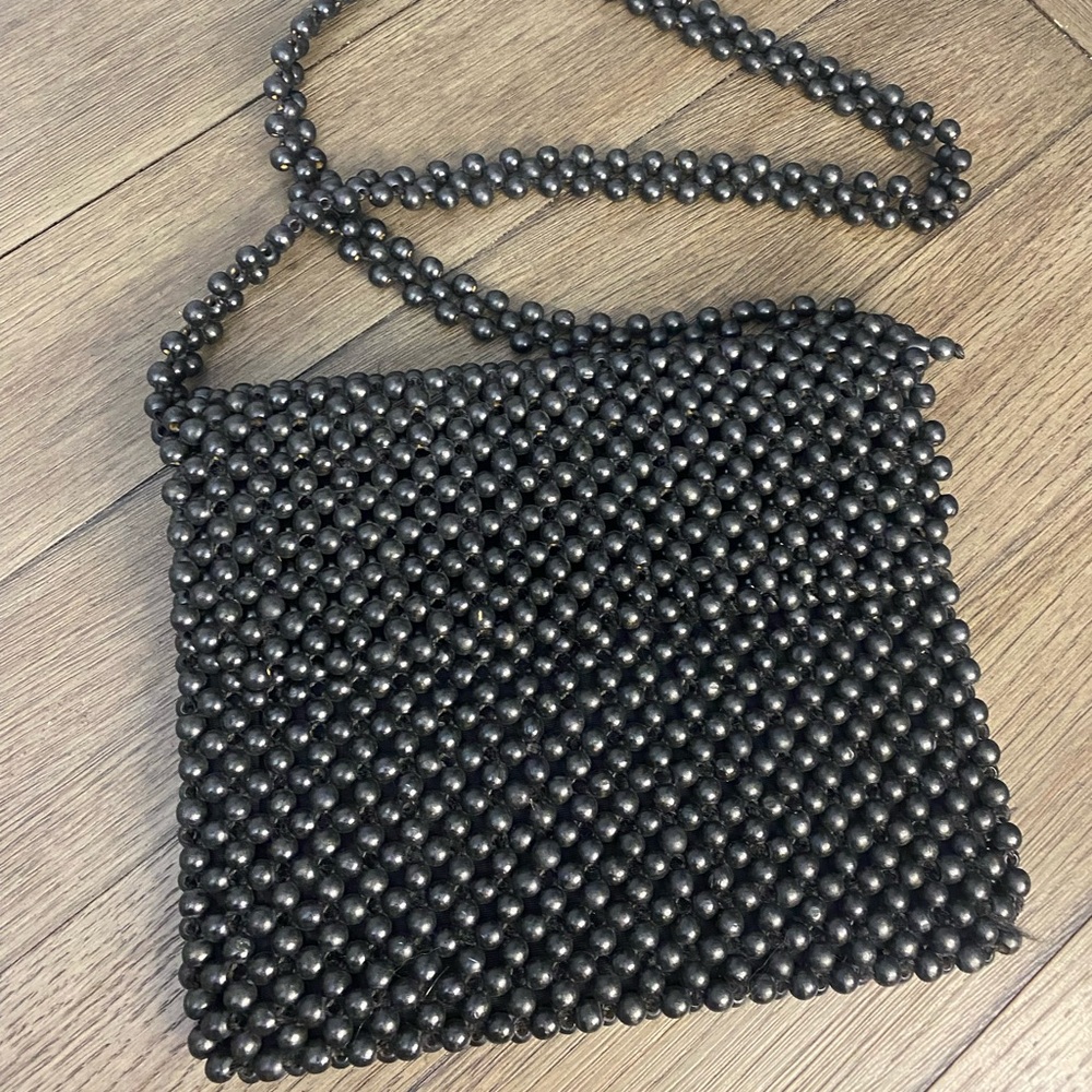 Vintage black beaded shoulder bag with zip closure and flap.